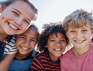Close up of pre-teen friends in a park smiling to camera