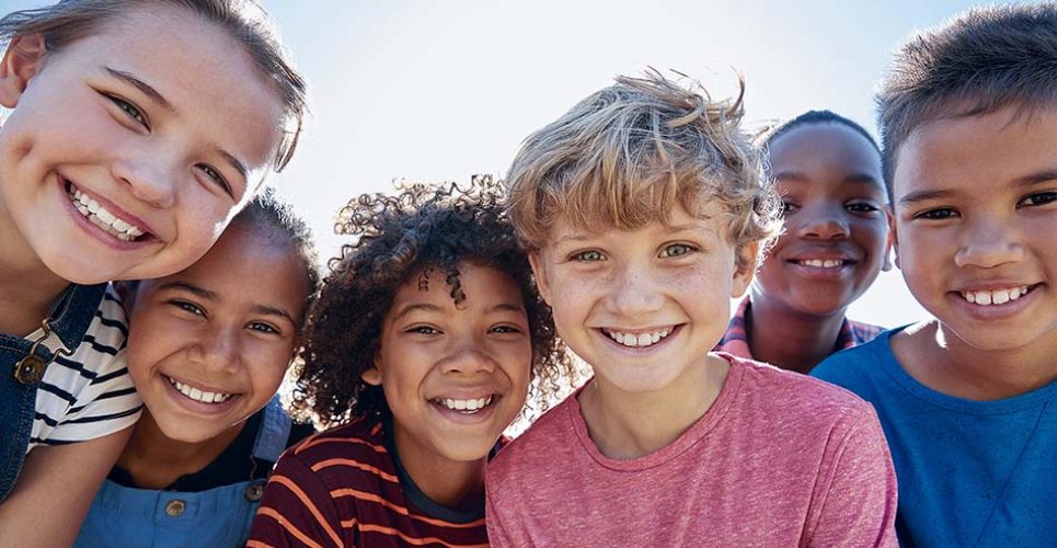 Close up of pre-teen friends in a park smiling to camera